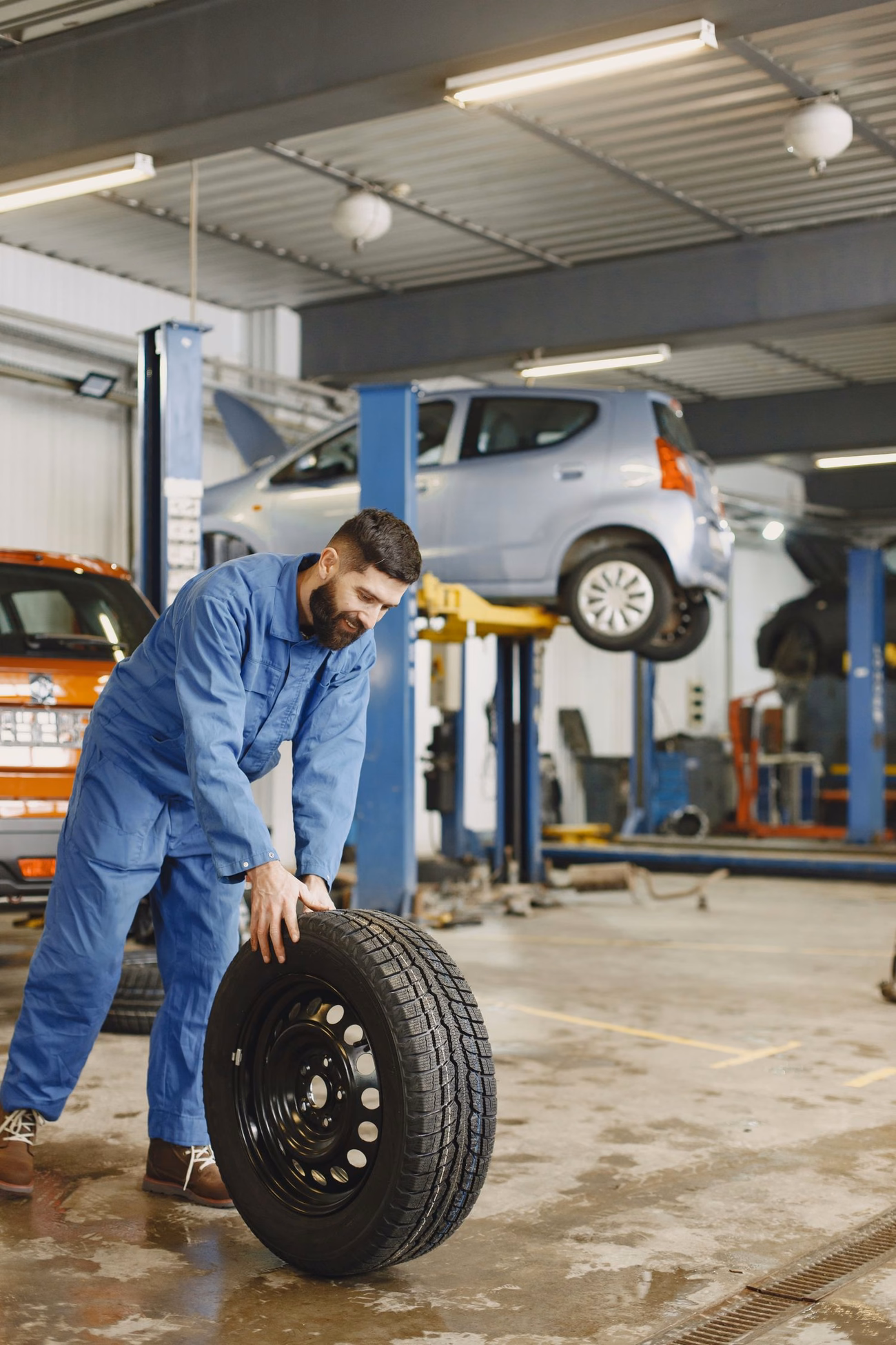 Mécanicien portant un pneu dans un atelier automobile